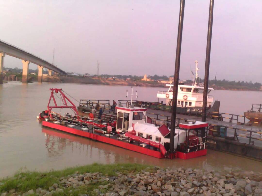 Red cutter suction dredger with spuds raised beside a bridge in Lekki, Lagos
